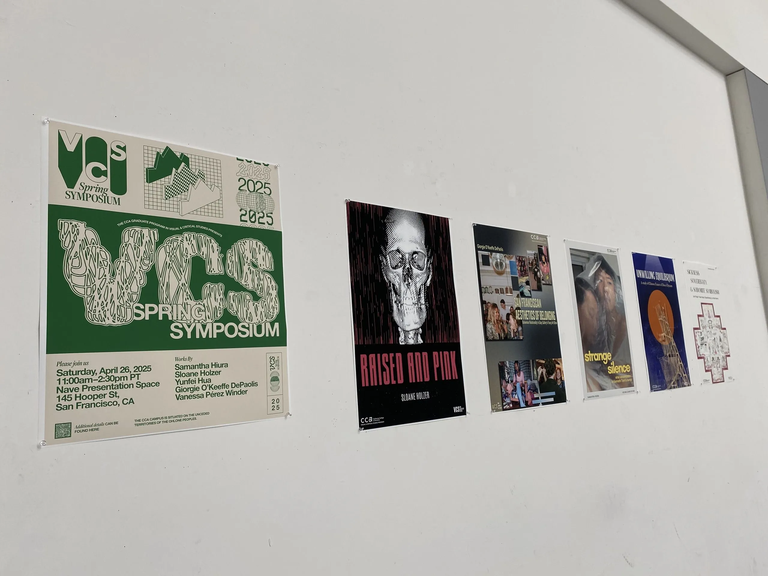 A gallery wall displays the 2025 VCS Spring Symposium event poster alongside five thesis project posters with varied graphic designs and typography.