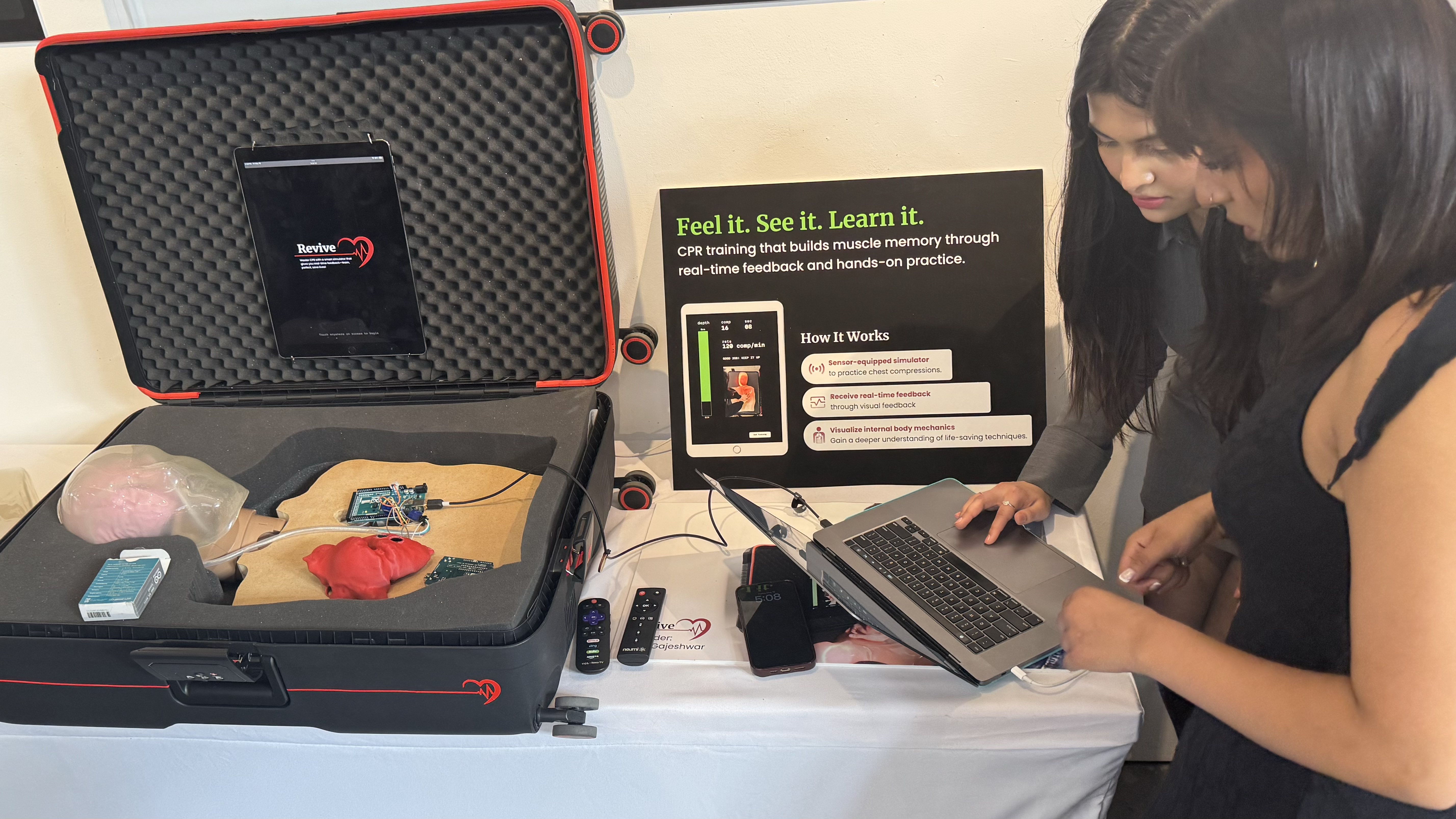 A student demonstrates the Revive CPR training device, which uses a sensor-equipped chest compression simulator and real-time tablet feedback.
